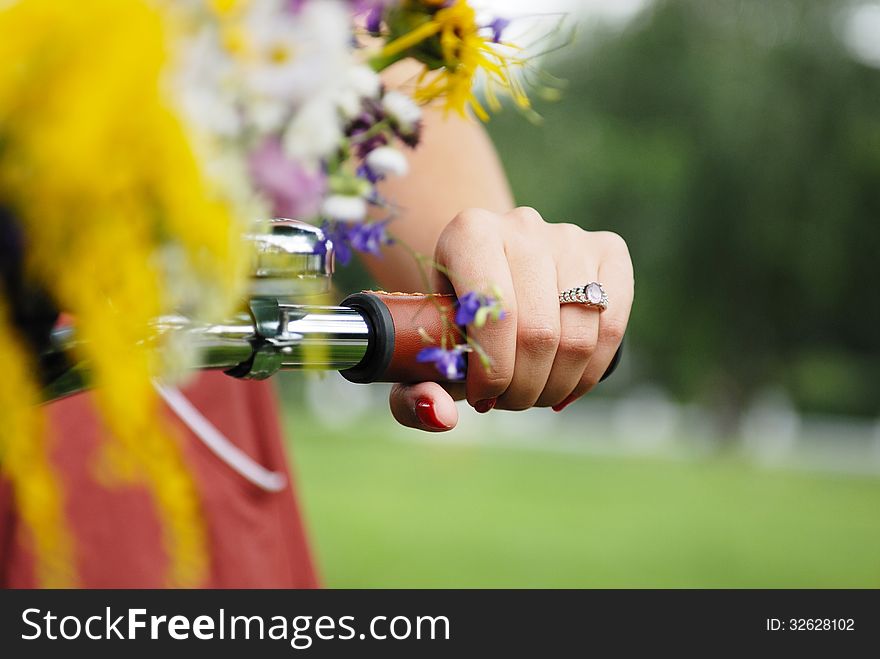 Close-up hand of young pretty woman with bicycle and flowers