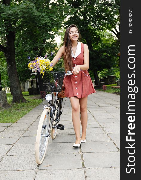 Fashion portrait of young pretty woman with bicycle and flowers