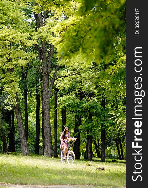 Fashion portrait of young pretty woman with bicycle and flowers