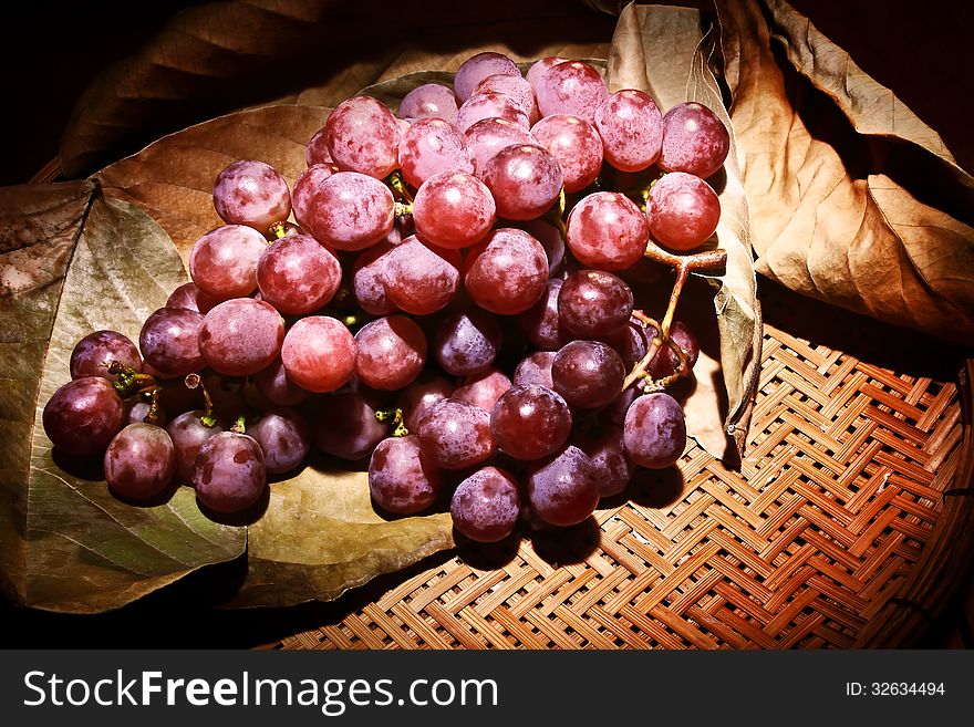 Bamboo basket of grapes with leaf background