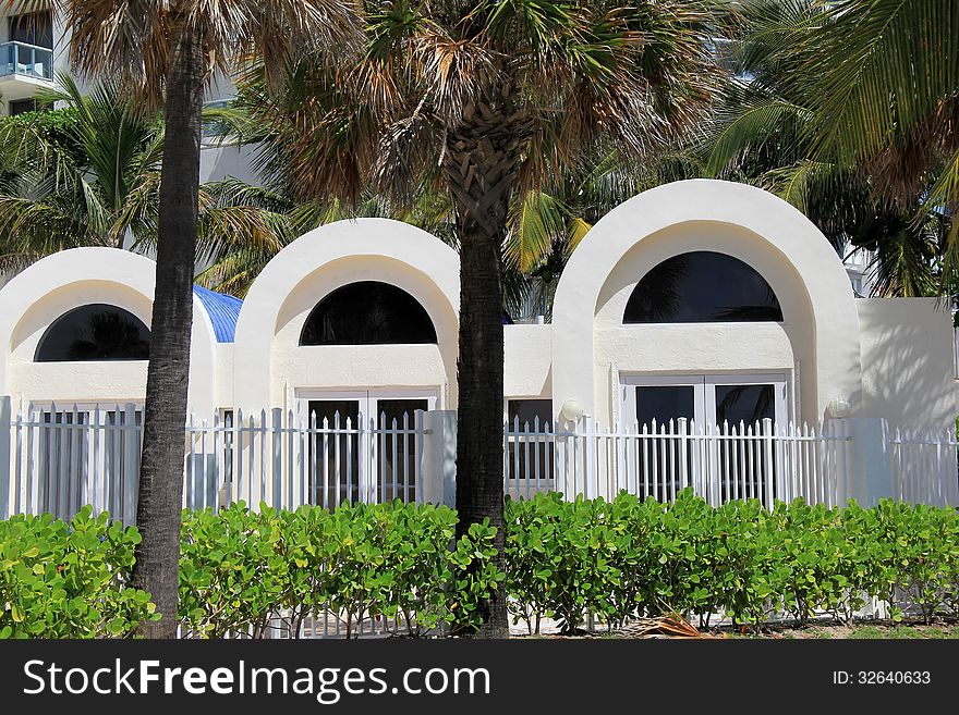 Beautiful palm trees in front of arched doorways in tropical setting with manicured shrubs in front. Beautiful palm trees in front of arched doorways in tropical setting with manicured shrubs in front.