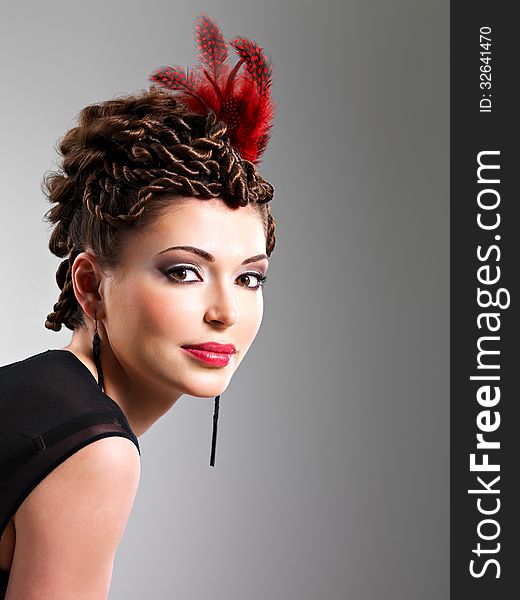 Woman with fashion hairstyle with red feather in hairs