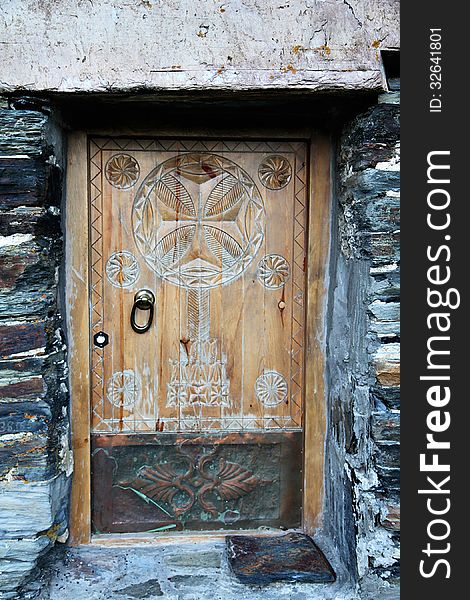 Vintage wooden door with ornament on stone wall background