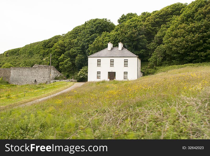 Rural Irish country farmhouse on a grassy hillside.