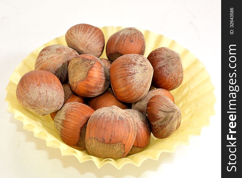 A small paper cup of hazelnuts in the shell.