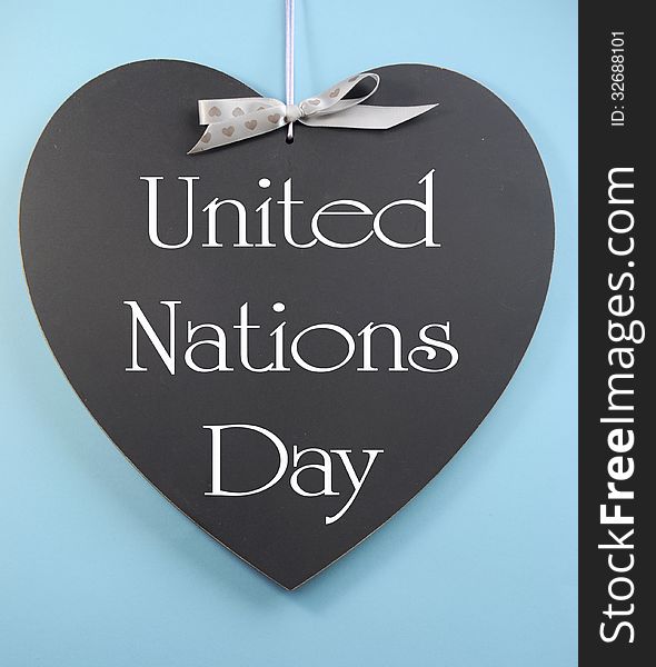 United Nations Day text message greeting written on heart shape blackboard against a sky blue background.