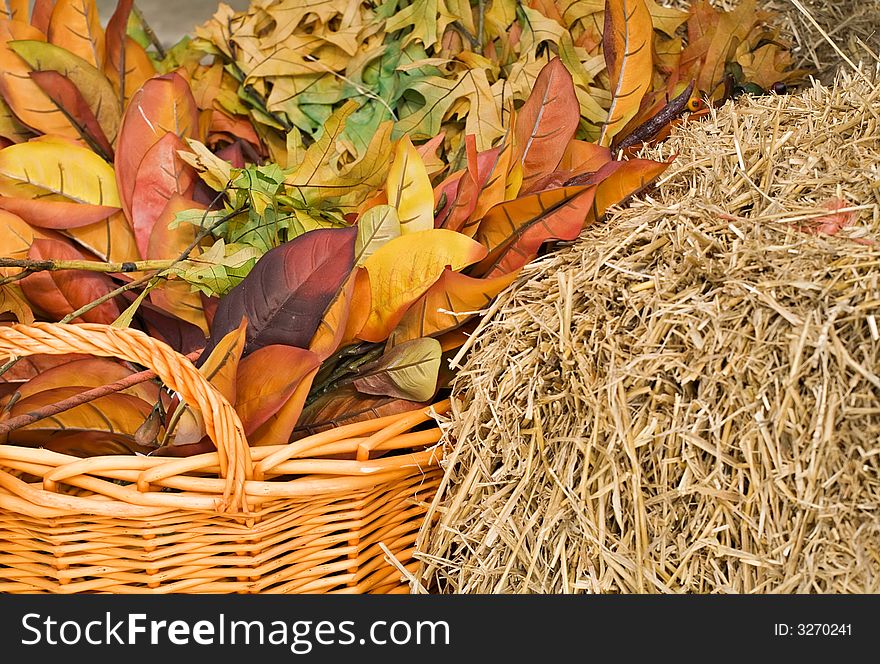 Autumn leaves and straw with a woven basket in warm colors for background. Autumn leaves and straw with a woven basket in warm colors for background.