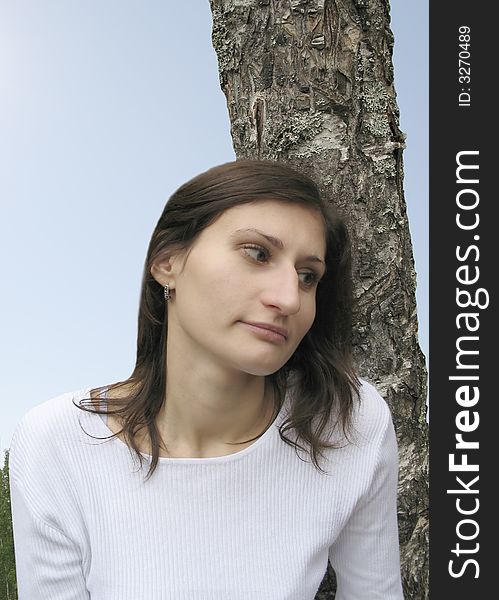 Pensive girl is on background of the tree