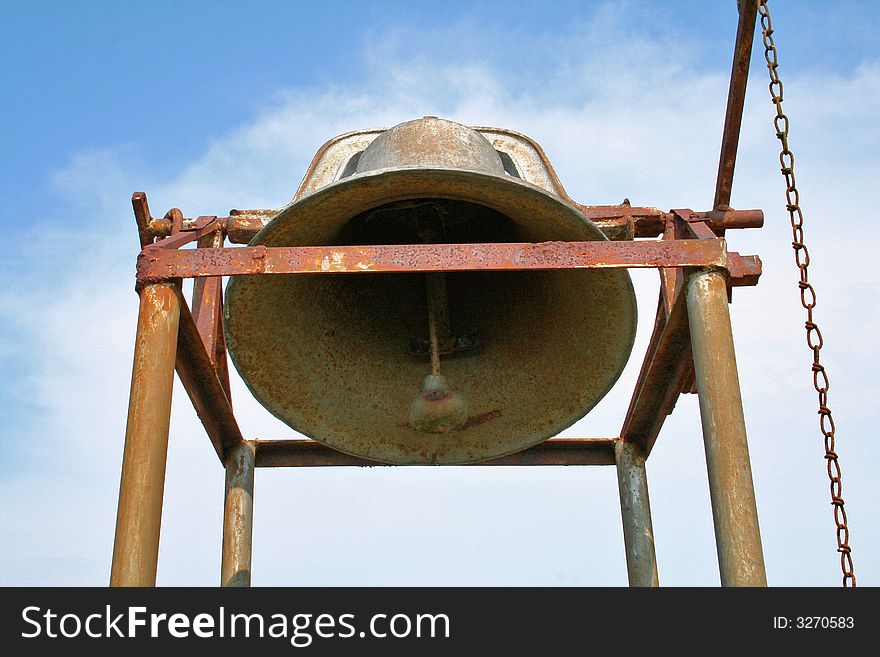 Antique, rusty bell in cemetery on poles with chain to ring it. Antique, rusty bell in cemetery on poles with chain to ring it