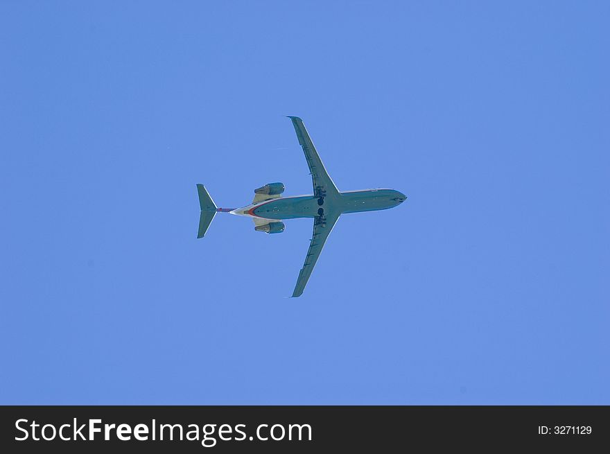 A jet flying overhead with a blue sky in the background. A jet flying overhead with a blue sky in the background