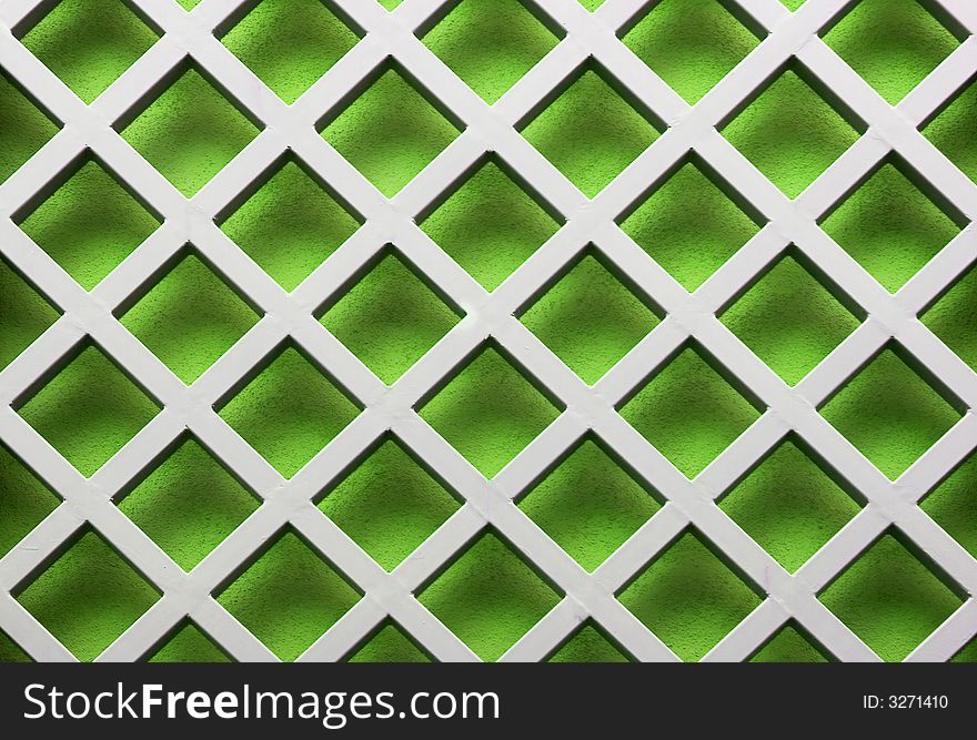 Image of a metal lattice over a green wall. Image of a metal lattice over a green wall