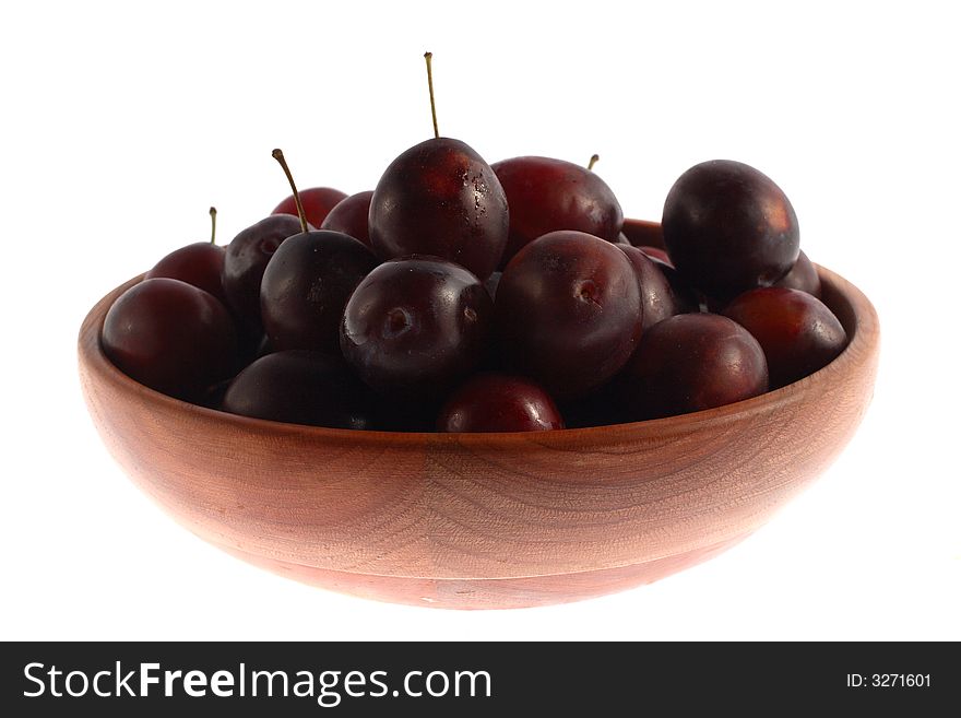 Plums in a big wood plate isolated. Plums in a big wood plate isolated