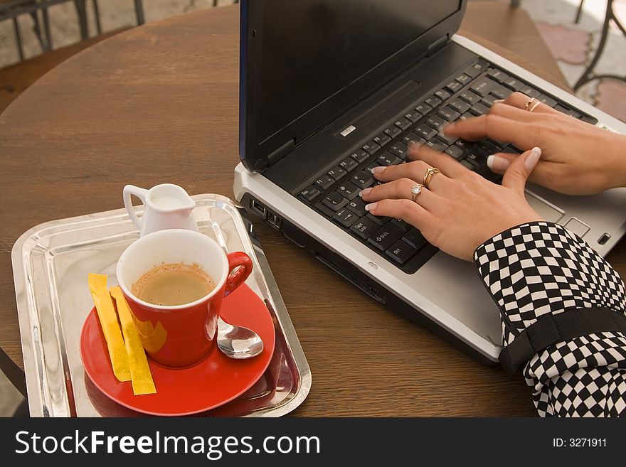 Detail image of woman hands typing on a laptop at a coffee table.Motion blur on fingers. Detail image of woman hands typing on a laptop at a coffee table.Motion blur on fingers.