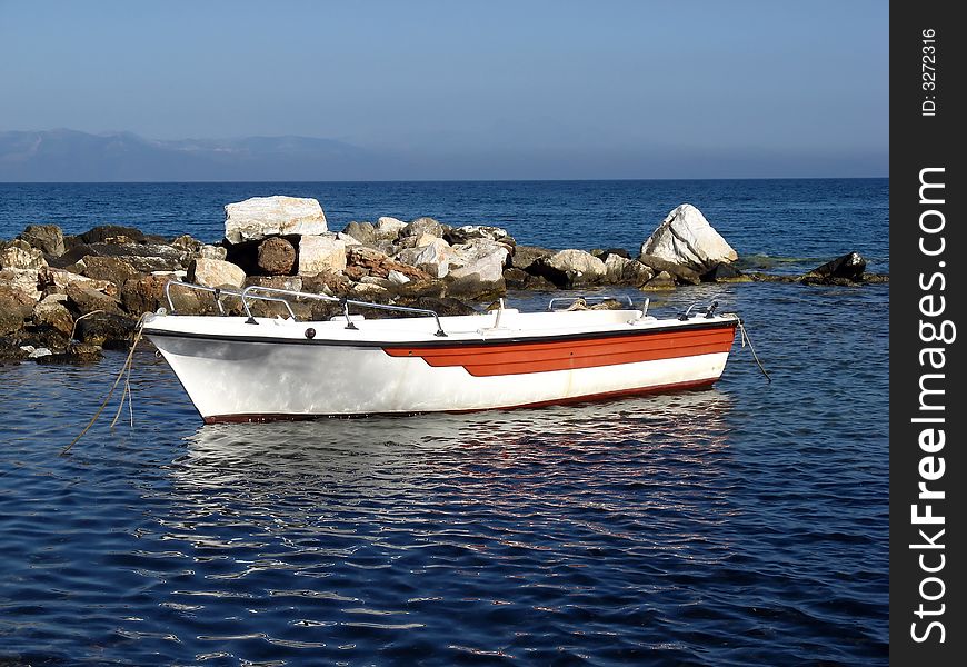A small white fishing boat docked at the coast