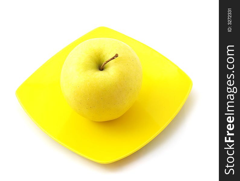 Yellow apple on the dish isolated on the white background