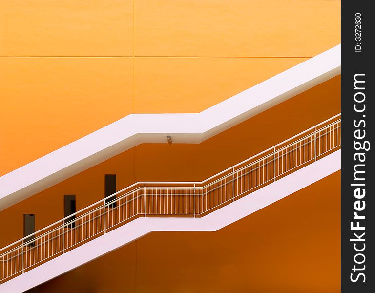 Staircase running diagonally up a freshly painted orange wall. Staircase running diagonally up a freshly painted orange wall.