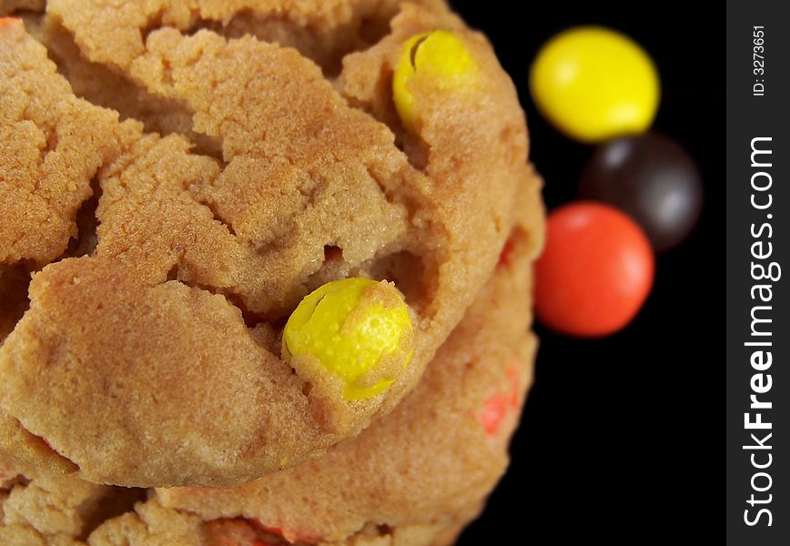 Close up photo of a stack of cookies with yellow, orange, and brown candy pieces.  Three pieces of the candy can be seen on the right side of the stack in the background. Close up photo of a stack of cookies with yellow, orange, and brown candy pieces.  Three pieces of the candy can be seen on the right side of the stack in the background.