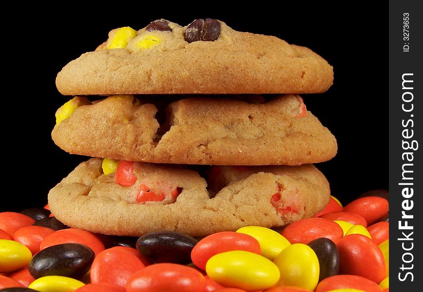 Three cookies stacked on top of orange, yellow, and brown candy pieces. Three cookies stacked on top of orange, yellow, and brown candy pieces.