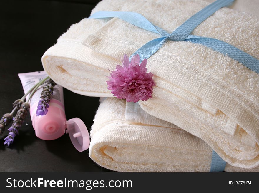 Hand cream and lavender next to a pile of towels
