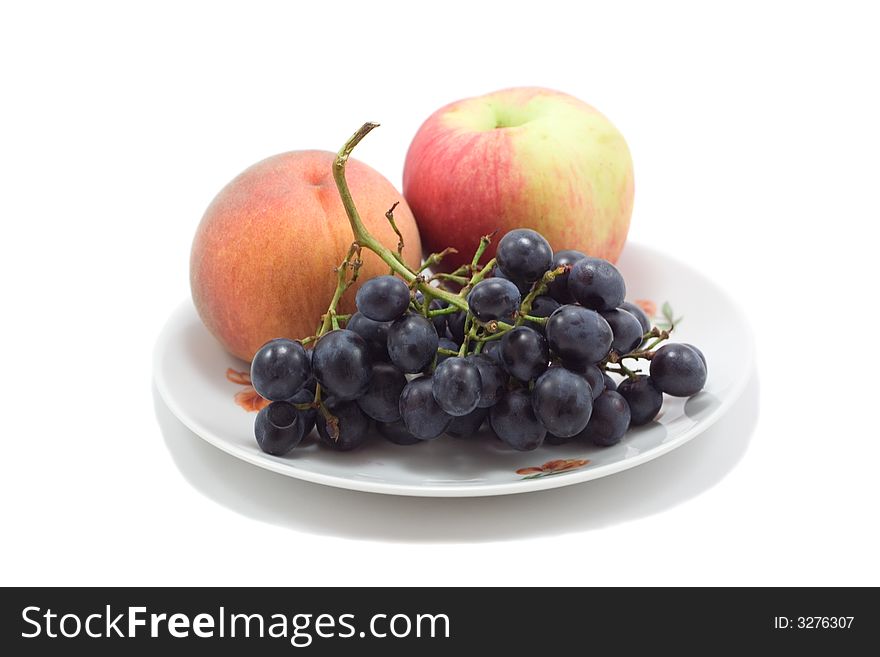 Plate with fruits, peach, apple and grapes, isolated on white