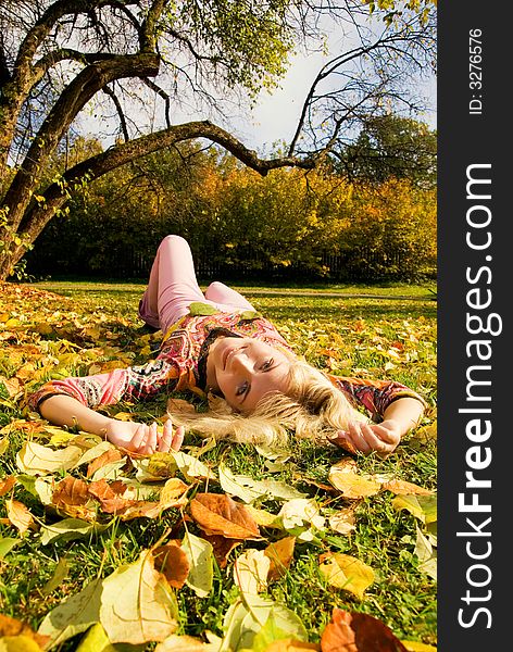 Beautiful blond girl lying on autumn leaves