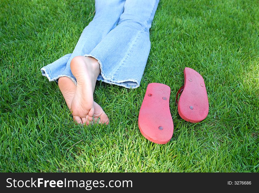This is a picture of a girl relaxing in the yard in her bare feet on a cool summer day.