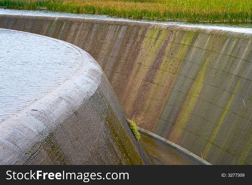 An overflowing dam with reeds. An overflowing dam with reeds