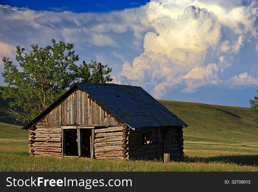 A thunderstorm builds behind a historic cabin on the prairie. A thunderstorm builds behind a historic cabin on the prairie.