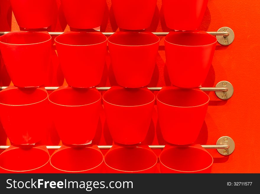 Row of red plastic cup hang on metal bar display on wall. Row of red plastic cup hang on metal bar display on wall