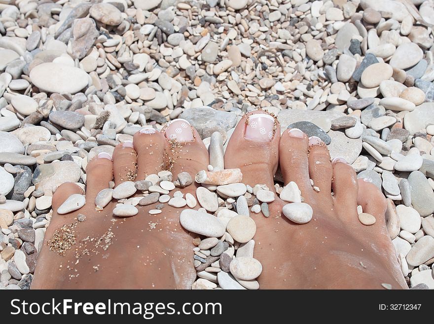 Womans feet in pebble in a beach, closup. Womans feet in pebble in a beach, closup.