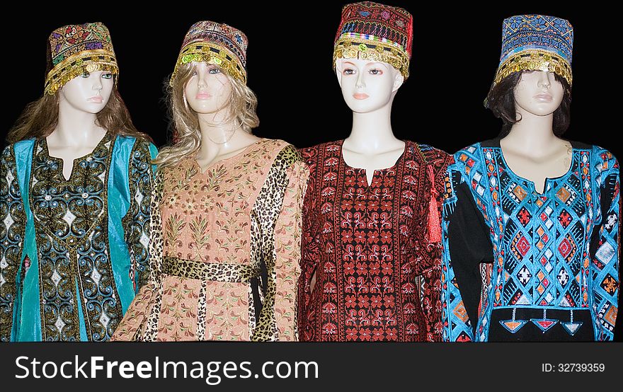 Four mannequins wearing traditional colorful Turkish costumes with headdresses, . Black background. Four mannequins wearing traditional colorful Turkish costumes with headdresses, . Black background.