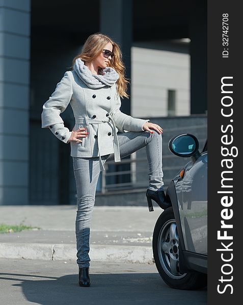 Young beautiful woman standing next to his gray car. Young beautiful woman standing next to his gray car