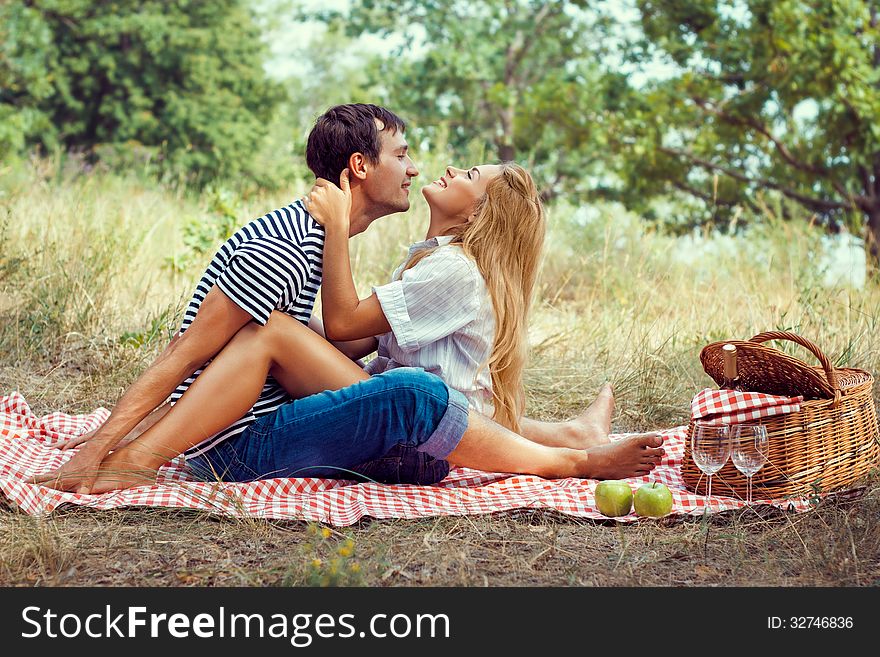 Young beautiful couple have a rest in wood on picnic, sitting face to face. Young beautiful couple have a rest in wood on picnic, sitting face to face