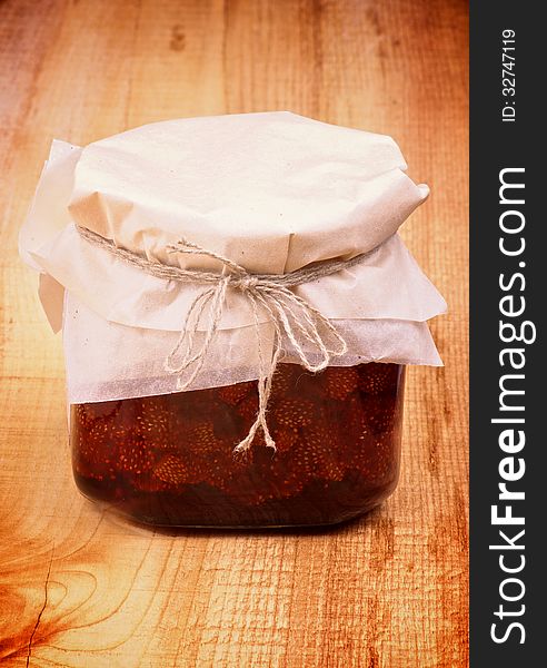 Wild Strawberry Jam Jar Covered with Butter-paper isolated on Wooden background