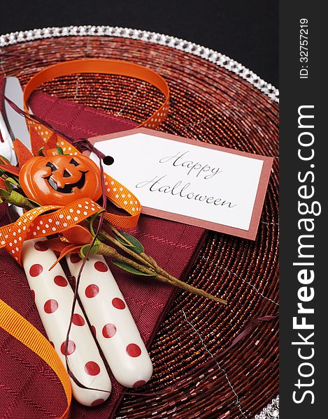 Happy Halloween table place setting with red polka dot cutlery and pumpkin decorations on a black tablecloth, Close up. Happy Halloween table place setting with red polka dot cutlery and pumpkin decorations on a black tablecloth, Close up.