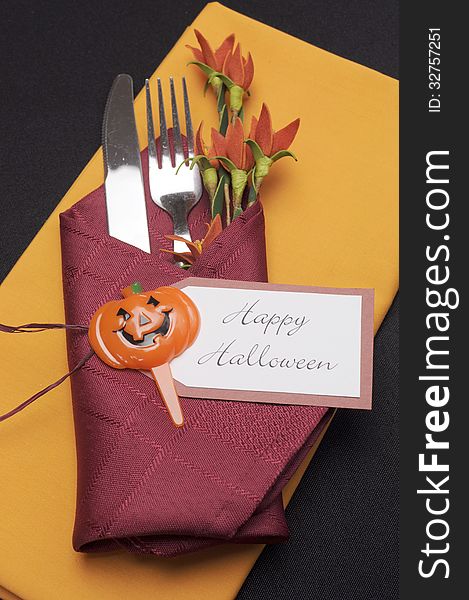 Happy Halloween table place setting with red and orange napkins on a black tablecloth, and halloween decorations. Aerial. Happy Halloween table place setting with red and orange napkins on a black tablecloth, and halloween decorations. Aerial.