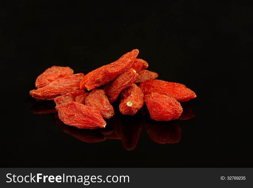 The photograph shows the goji berry placed on black mirror background. The photograph shows the goji berry placed on black mirror background.