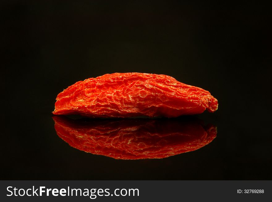 The photograph shows the goji berry umiszczonÄ… on czrnym mirrored background. The photograph shows the goji berry umiszczonÄ… on czrnym mirrored background.