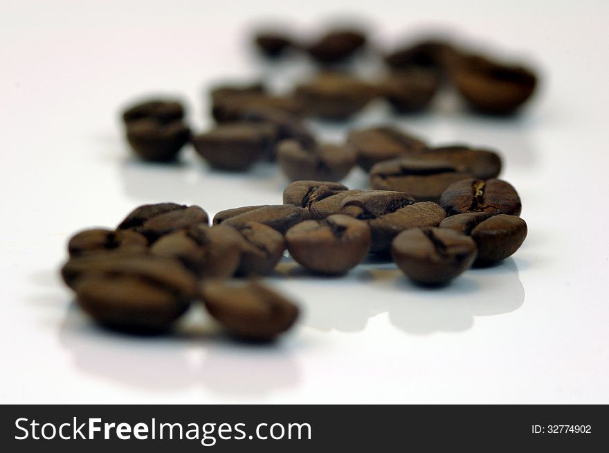 The photograph shows coffee beans placed on a white background. The photograph shows coffee beans placed on a white background.