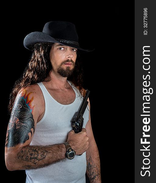 Very handsome man with long wavy brown hair and striking eyes wearing a black cowboy hat holding a revolver. Very handsome man with long wavy brown hair and striking eyes wearing a black cowboy hat holding a revolver