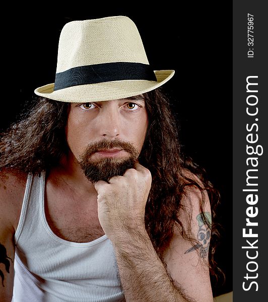 Very handsome man with long wavy brown hair and striking eyes wearing a straw fedora with a black band. Very handsome man with long wavy brown hair and striking eyes wearing a straw fedora with a black band