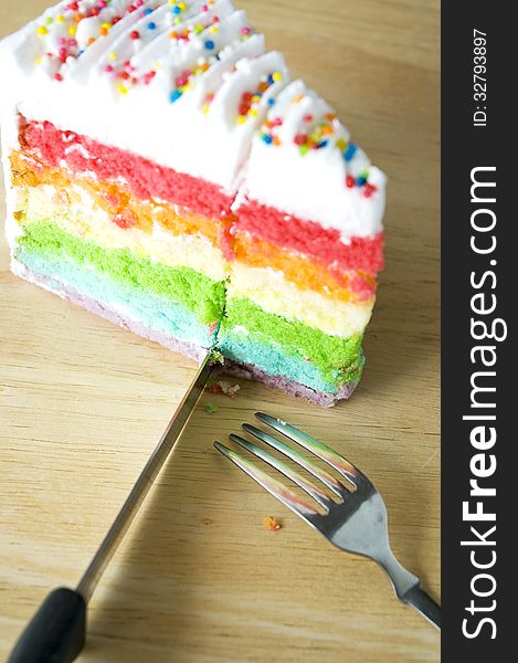 Cutting rainbow cake on wooden table. Cutting rainbow cake on wooden table