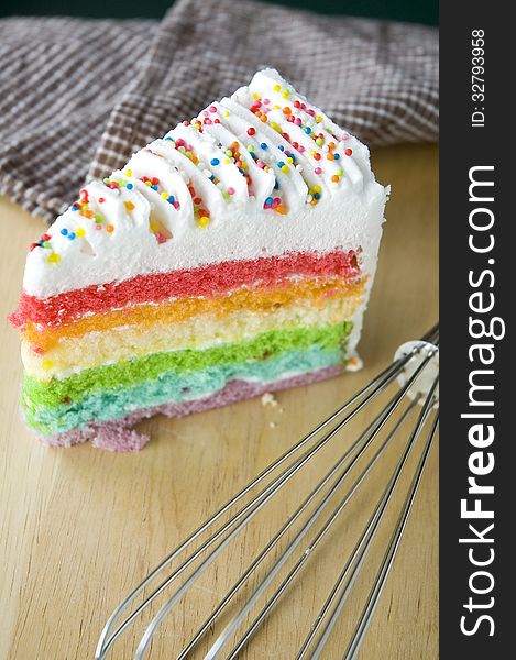 Rainbow cake put on wooden table with kitchenware. Rainbow cake put on wooden table with kitchenware