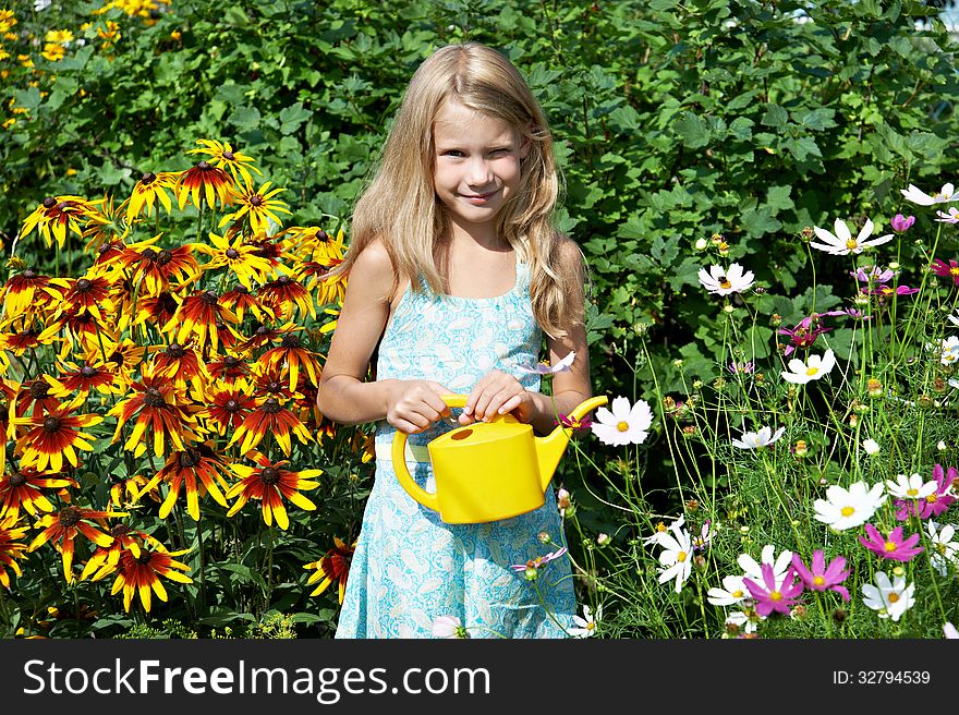 Little girl with watering can near flowers