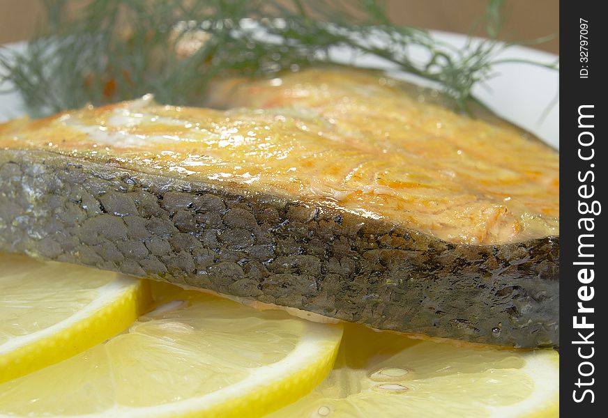 Fried salmon on a plate with lemon and dill