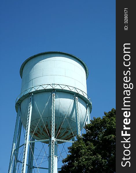 Blue Water Tower against a blue sky and tree