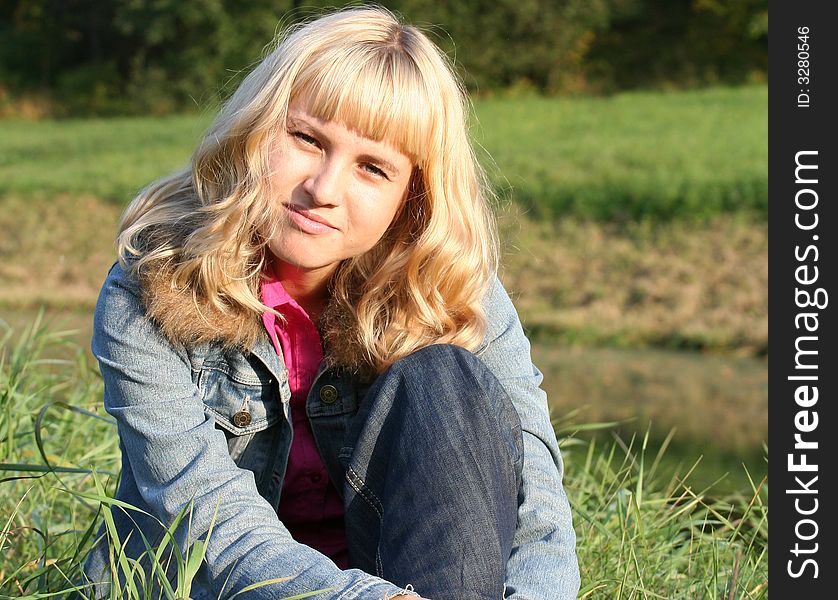 Young blond woman is sitting on a grass. Young blond woman is sitting on a grass
