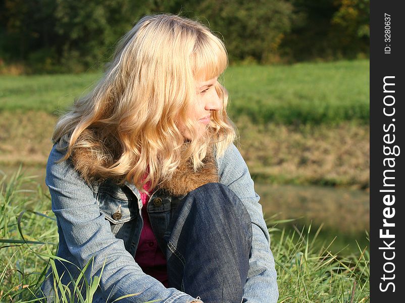 Young blond woman is sitting on a grass. Young blond woman is sitting on a grass