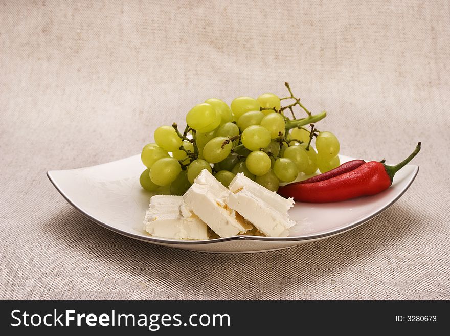 Food components composition containing  red peppers, white grapes and cheese on white plate