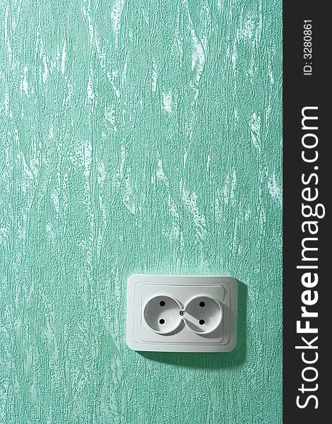 Electric wall plug at a green wall